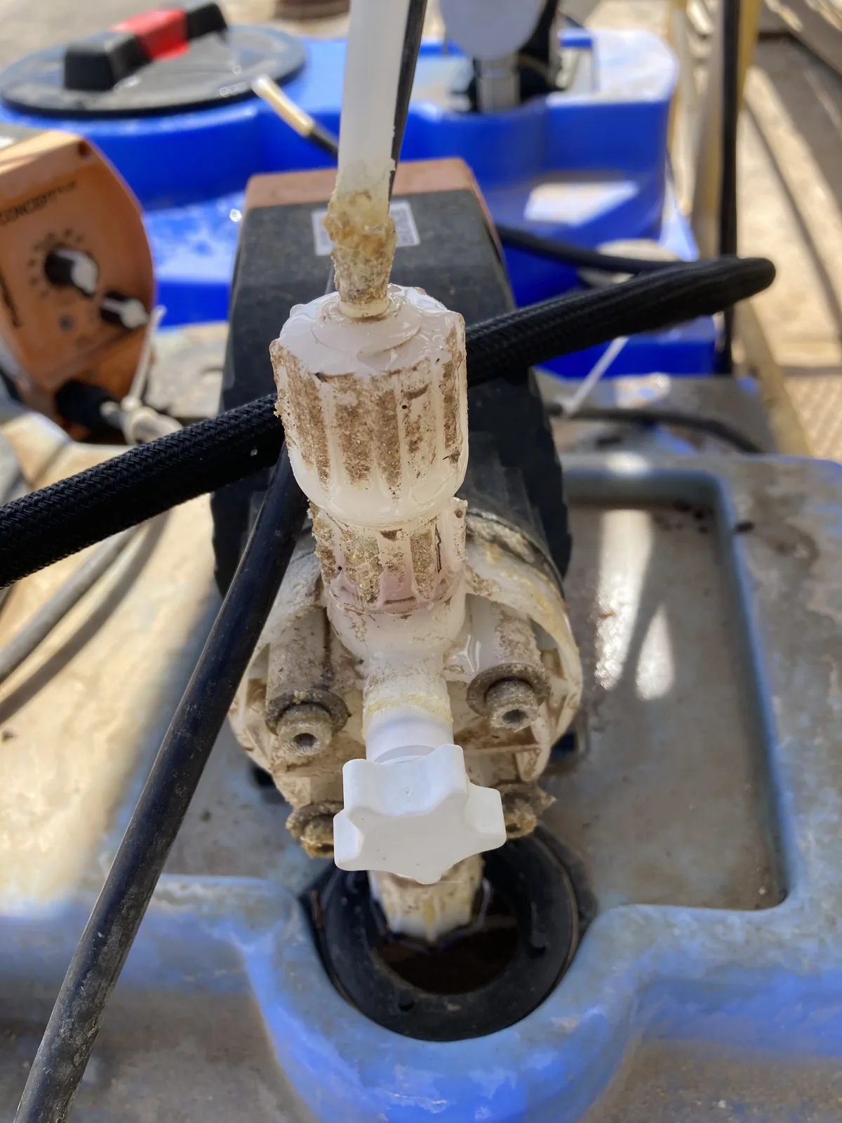 Chemical metering pump head and fittings coated in crusty tan residue